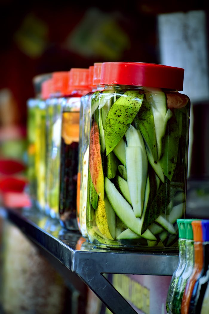 Colorful jars of pickled mangoes showcasing vibrant tropical fruit preserved in brine.