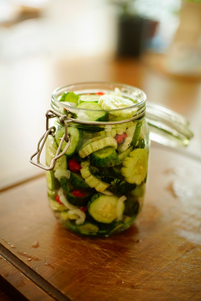 Glass jar filled with fresh homemade pickled cucumbers on wooden surface, ideal for healthy food concepts.